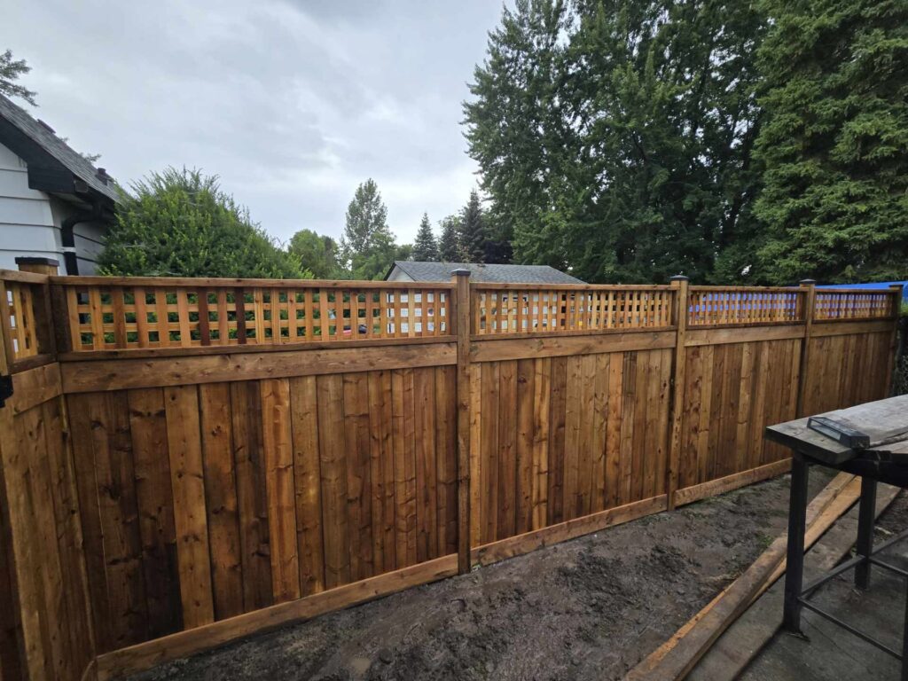 a backyard wood privacy fence with lattice top and post caps