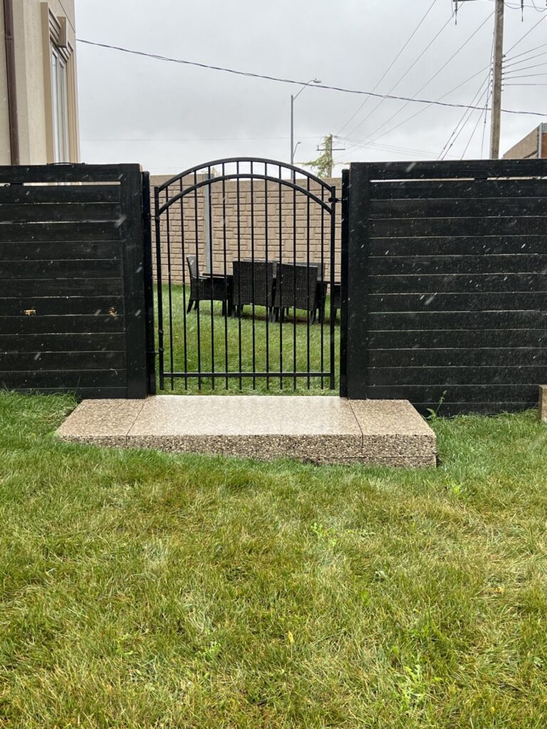 Arched iron gate attached to horizontal vinyl fence