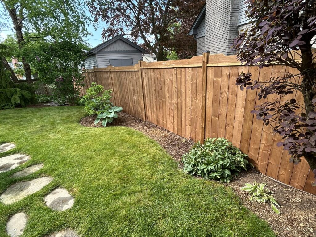 horizontal top rail wood privacy fence in a backyard down by the garden