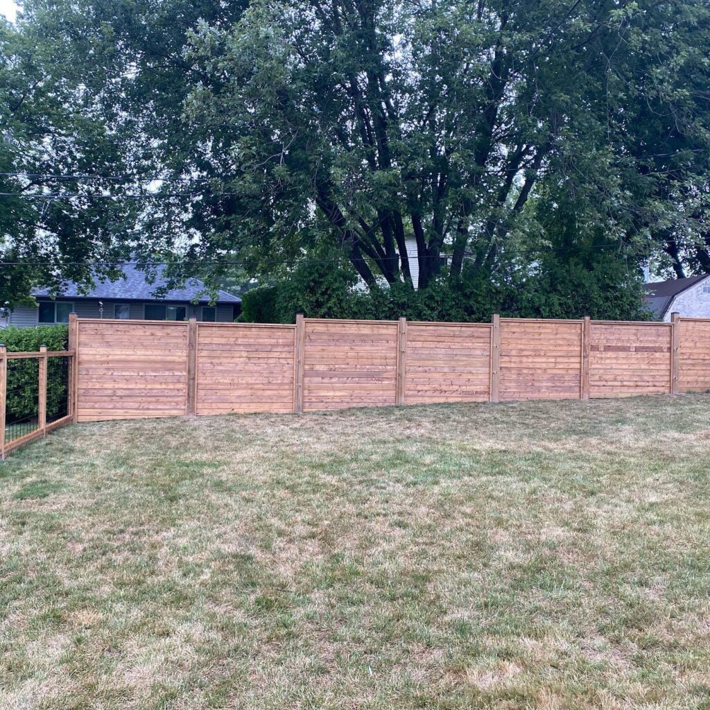 Stepped horizontal wood fence in a backyard on grass