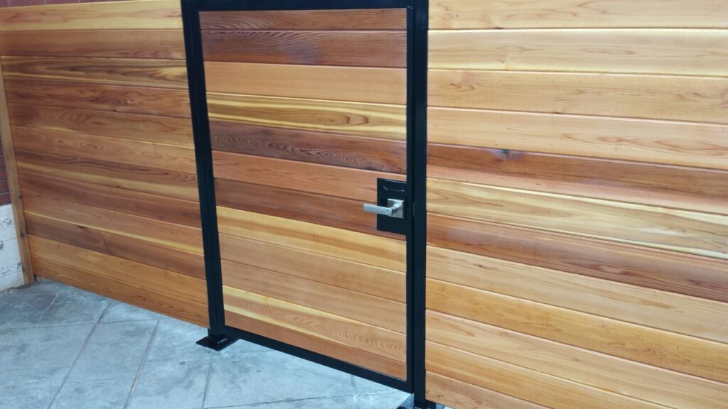 Custom horizontal wood fence and gate with metal posts on patio tiles.