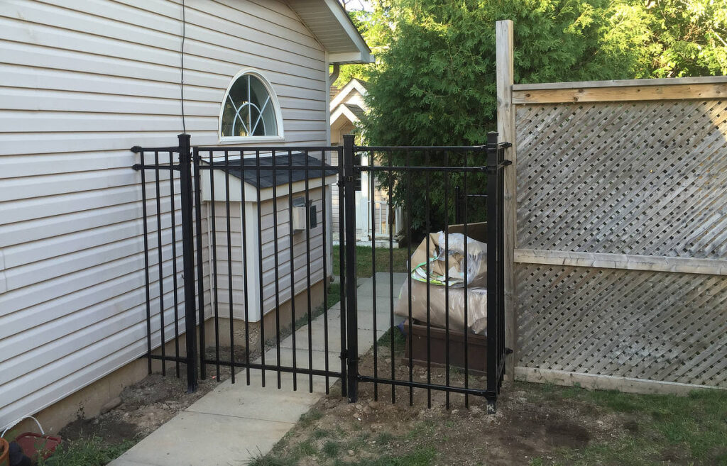 Simple iron gate attached to wood fence and house