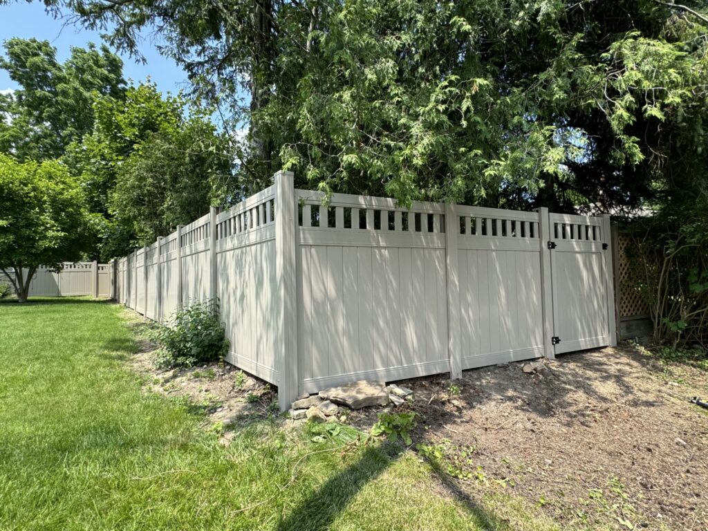 a vinyl fence with picket top and a single gate through a backyard.