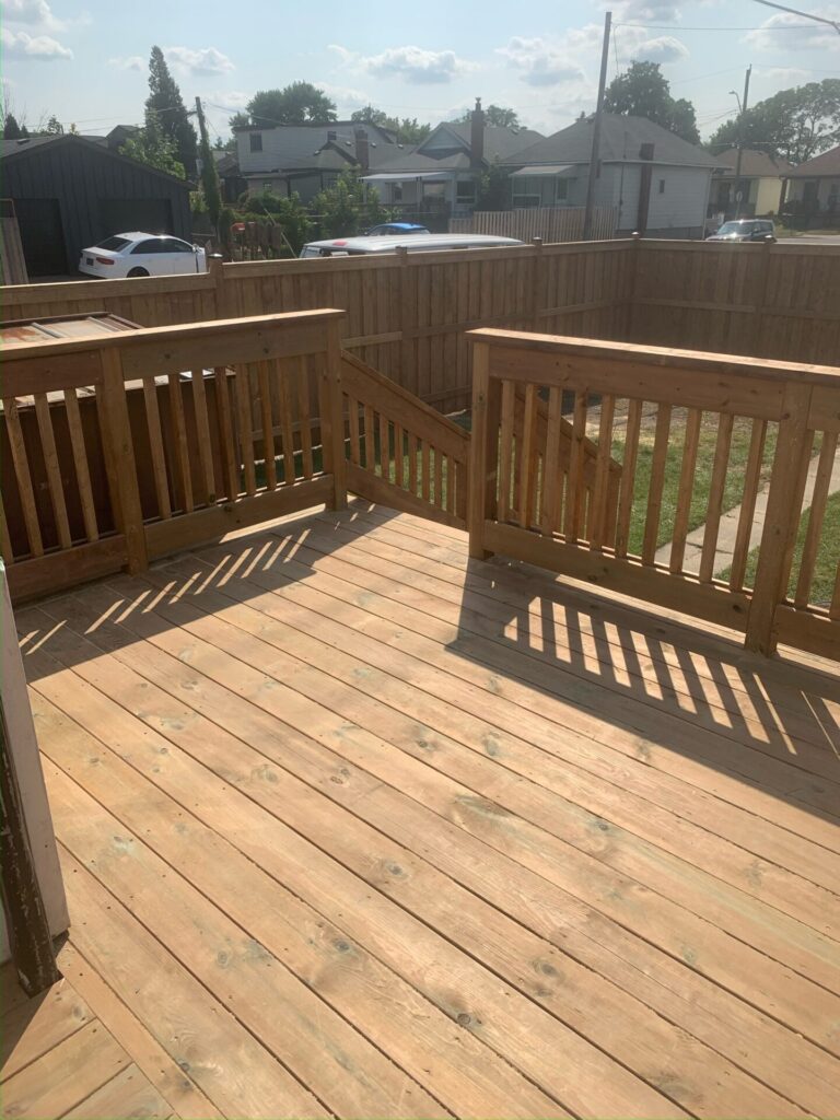 View of backyard wooden deck with railings and stairs from the door